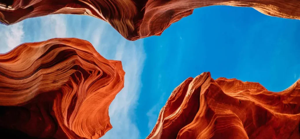 Vivid blue sky between undulating red sandstone canyon walls.