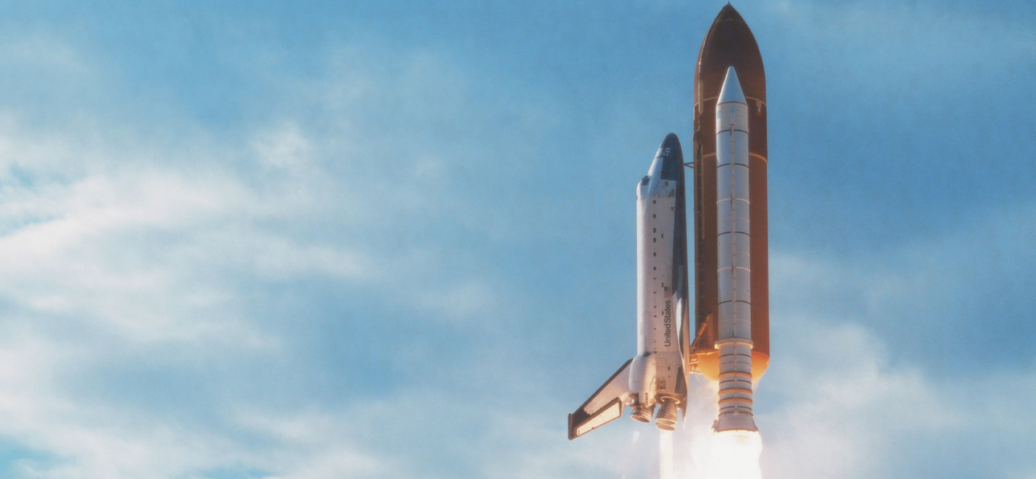 A space shuttle ascends into the sky, leaving a trail of smoke as it begins its journey into space.