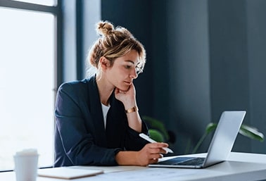 Woman looking at laptop while resting her head on her hand