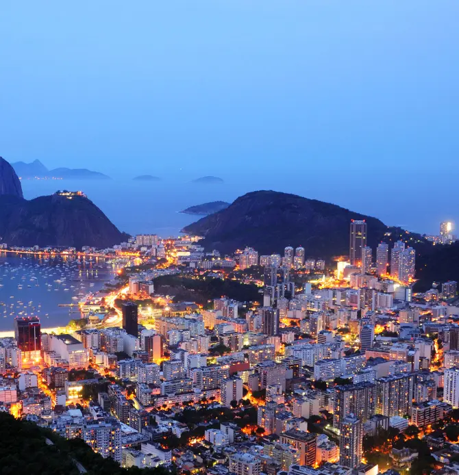 A brightly lit cityscape at night with a prominent illuminated tower at the center.